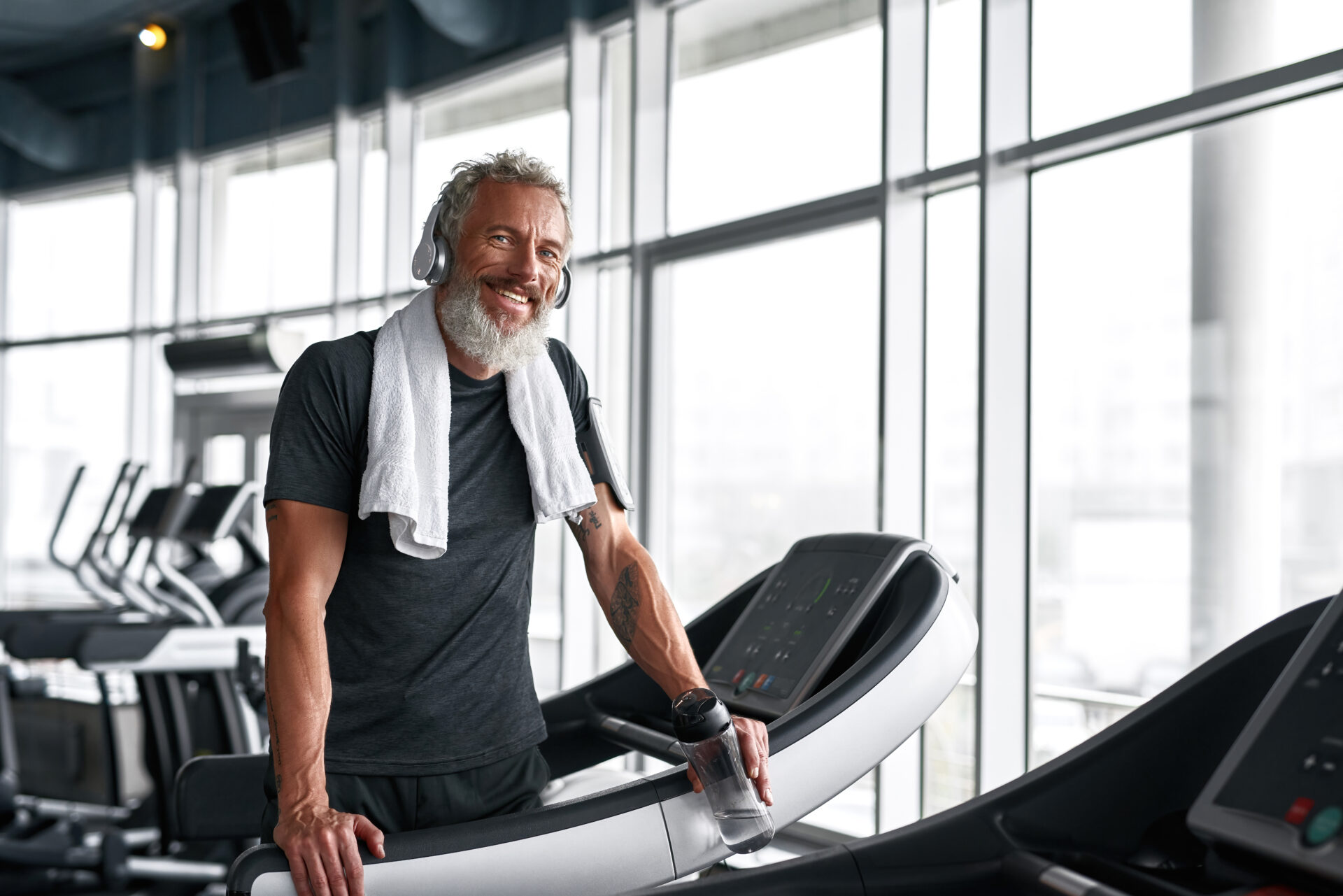 Cheerful Grey Haired Man With Towel Around Neck, Posing In Gym